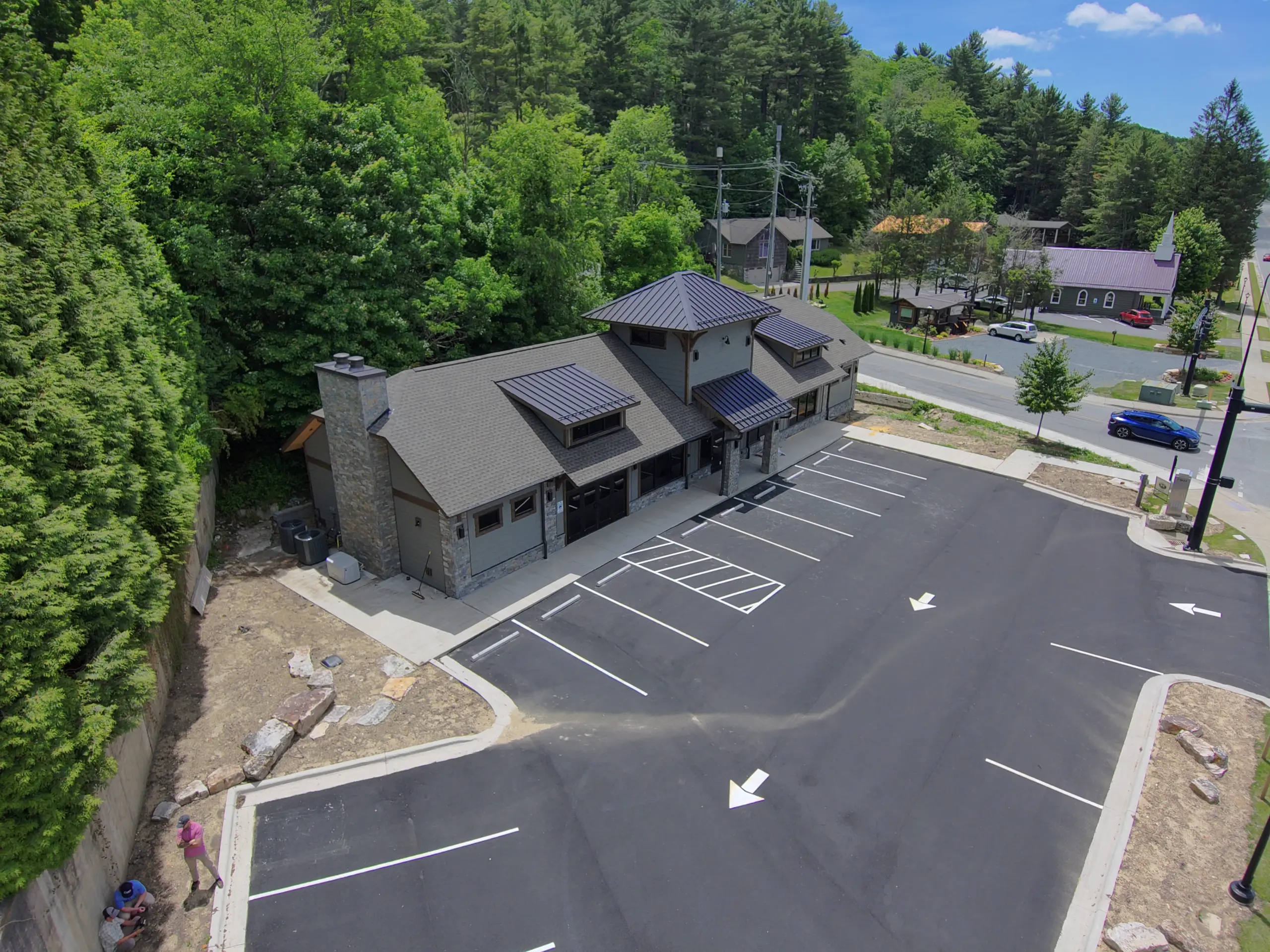 Aerial view of The Lodge retail building in Blowing Rock, NC, showing the stone chimney, gable roof design, and exterior entrance.