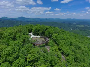 Aerial view of Howard Knob Overlook, a curved elevated walkway looping over an overlook with the Blue Ridge Mountains behind.